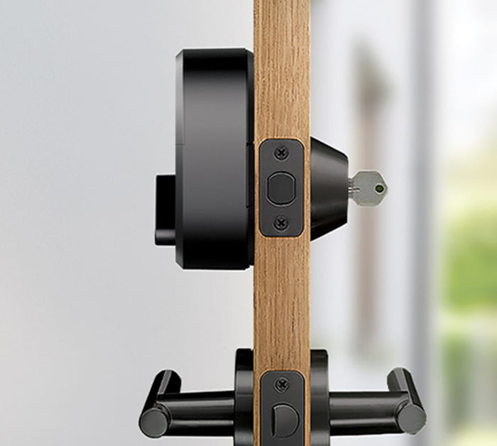 The side view of a black august lock on a door with a key in the lock