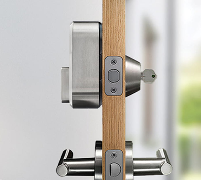 The side view of a silver august lock on a door with a key in the lock