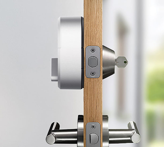 The side view of a silver august lock on a door with a key in the lock