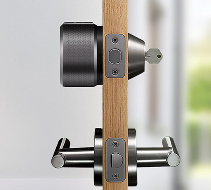 The side view of a black august lock on a door with a key in the lock