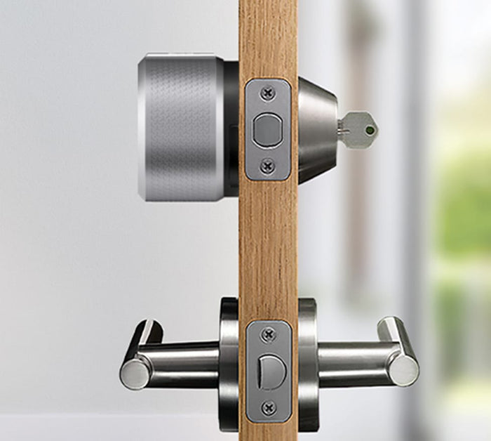 The side view of a silver august lock on a door with a key in the lock