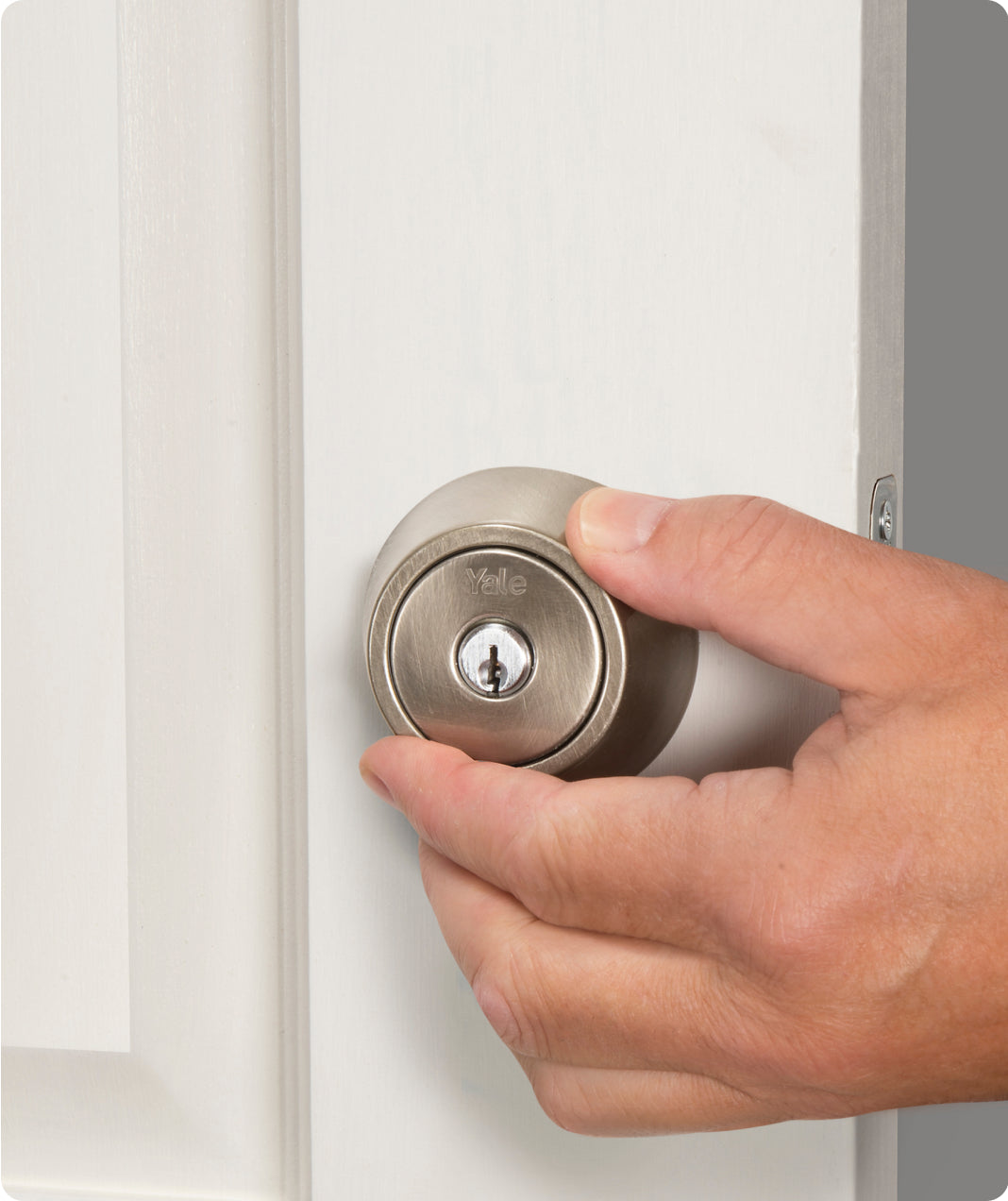A man touching a silver Yale lock