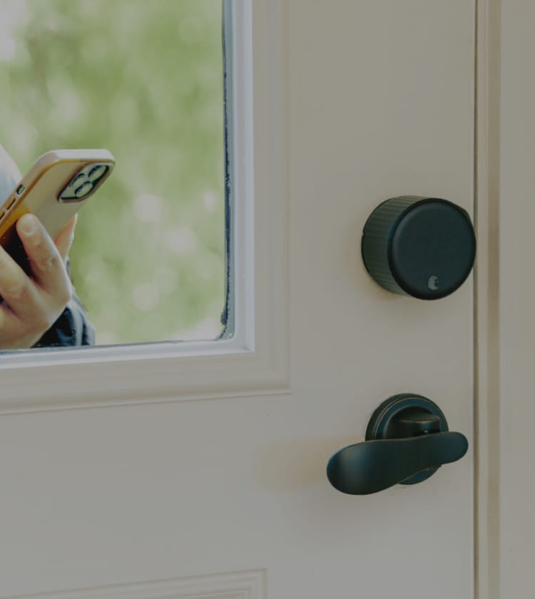 August smart lock pro in dark gray shown with a lever handle on the interior of a door 