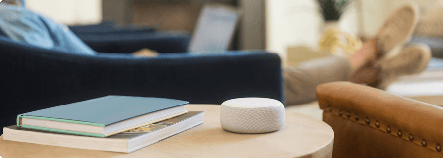 A man relaxes in his living room with a google nest smart speaker