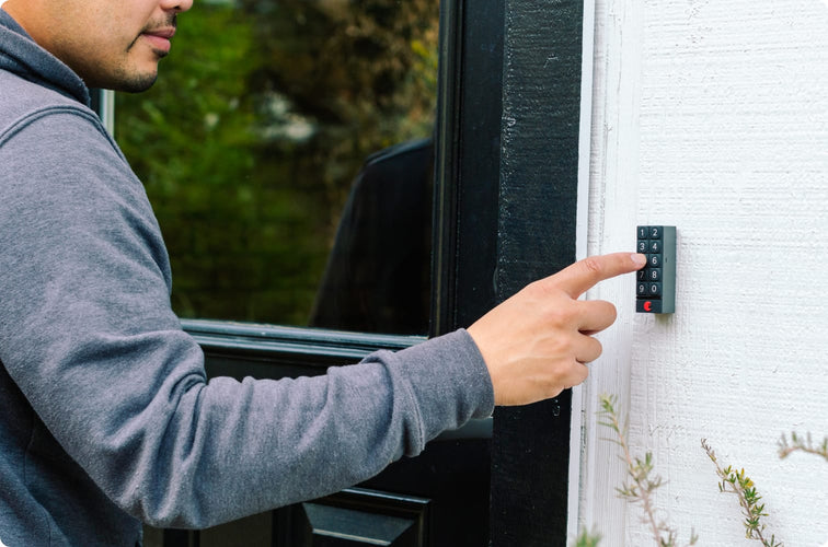 A man wearing a long sleeve shirt pushes buttons on an August Home keypad door lock to unlock his door without keys