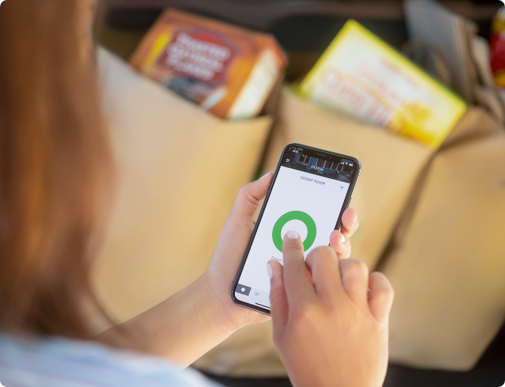 Woman with groceries in the trunk of her car unlocking her door with her phone