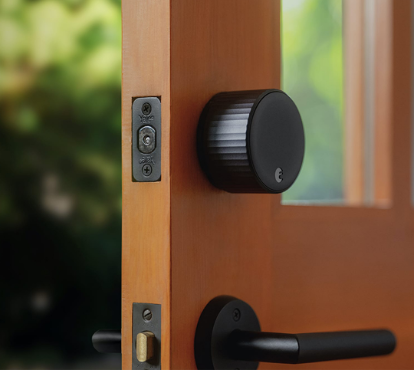 A black August wifi lock on an open door