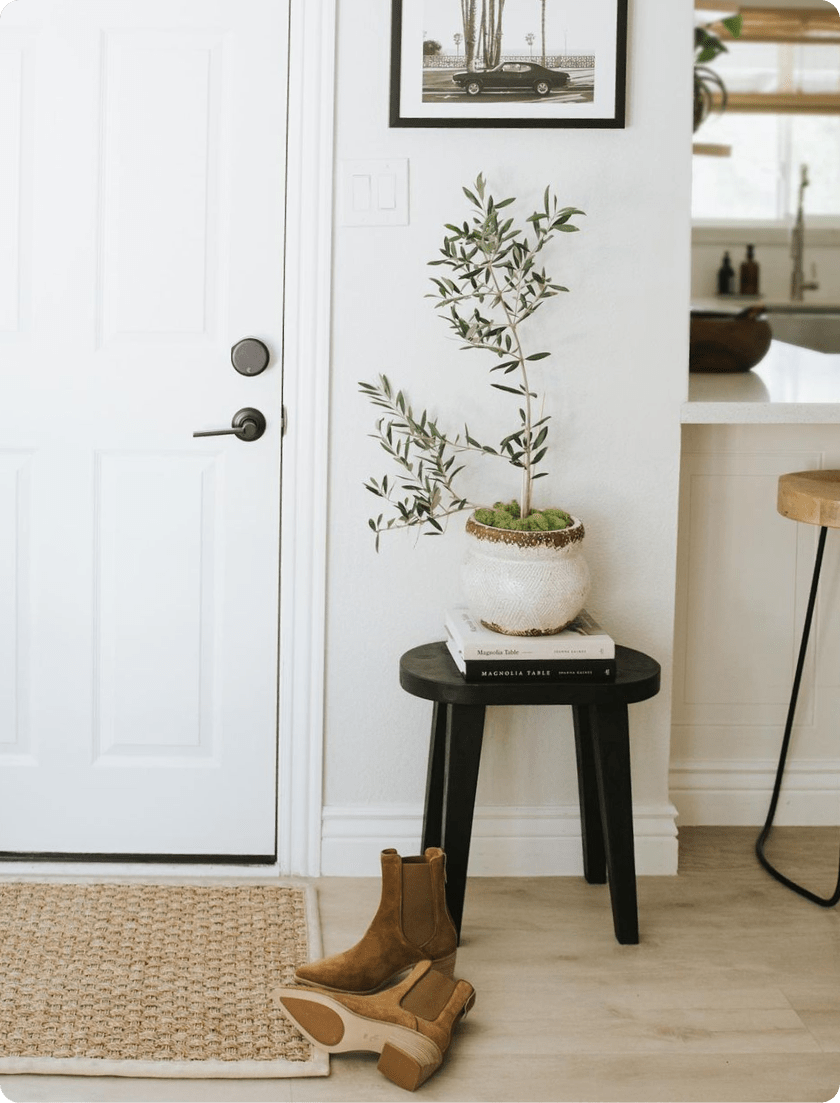 A potted plant on a stool next to a white door with August smart locks installed